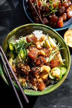 two bowls filled with rice and vegetables next to chopsticks on a table top