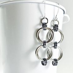 A simple little twist on basic hoops! These are my everyday earrings. Really, I wear these all the time, and you will too! Each earring consists of a double set of intertwined aluminum loops connected with dark gray links. • 2 1/2 inches long • lightweight aluminum • elongated silver plated ear Simple Nickel-free Metal Earrings, Grey Pearl Earrings, Hoop Earrings Handmade, Chainmail Jewelry, Aluminum Jewelry, Earrings Handmade Dangle, Dangle Hoop Earrings, Silver Dangle Earrings, Trendy Earrings