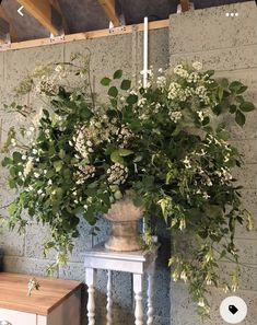 a vase filled with white flowers on top of a table next to a wooden dresser