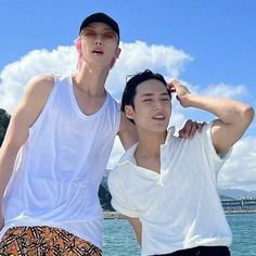 two young men standing next to each other near the ocean