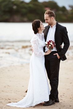 a bride and groom are standing on the beach