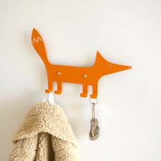 an orange coat rack with a key hanging from it's side and a stuffed animal on the other side