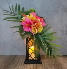 a vase with flowers and greenery on a wooden table next to a candle holder