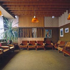 a large room with couches, chairs and pictures on the wall above them is decorated with wood paneling