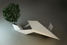 a plant is growing out of an origami airplane shaped table that sits on wheels