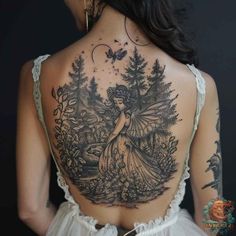 a woman with tattoos on her back is standing in front of some trees and flowers