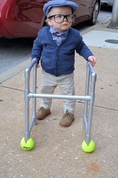 a little boy with glasses and a hat on standing next to a metal walker