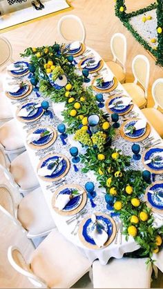 the table is set with blue and yellow plates, place settings, and greenery