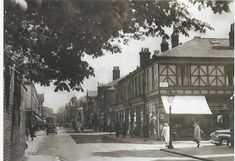 an old black and white photo of people walking down the street in front of buildings