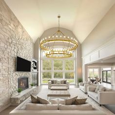 a large living room with white couches and a chandelier hanging from the ceiling