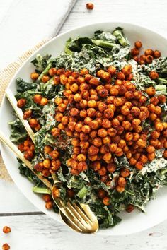 a white plate topped with lettuce and chickpeas next to a fork