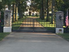 an iron gate with american flags at the entrance to a large home in the background