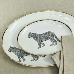 two white and gold plates with black leopards on them