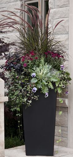 a large planter filled with lots of flowers next to a door way and steps