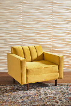 a yellow chair sitting on top of a rug in front of a wall with waves