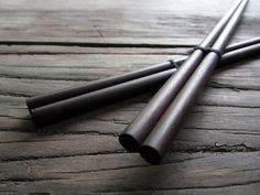 three black sticks laying on top of a wooden table