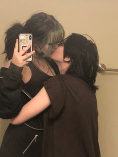 two people taking a selfie in front of a mirror with their cell phones up to their faces