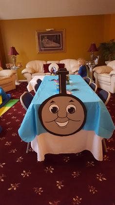 a table with a thomas the train design on it in a room filled with couches and tables