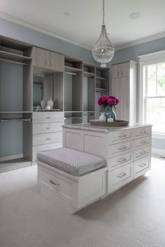 a large walk in closet filled with lots of white drawers and cabinets next to a chandelier