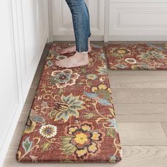 a person standing on the floor in front of two rugs that have flowers on them