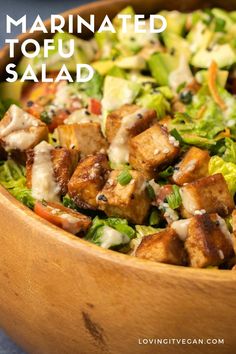 a wooden bowl filled with lettuce and meat on top of a blue table