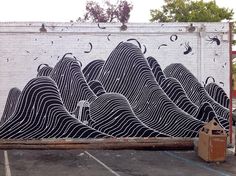 a mural painted on the side of a building with black and white waves in front of it