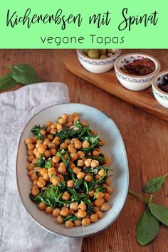 a white bowl filled with chickpeas and spinach on top of a wooden table