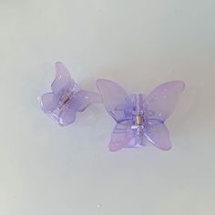 two purple butterfly clips sitting on top of a white surface