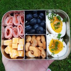 an open lunch box with eggs, sausages, blueberries and other food items