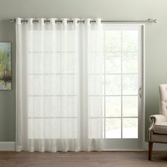 a living room with white curtains and a chair