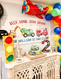 a birthday party with balloons and decorations on the wall, including a firetruck cake