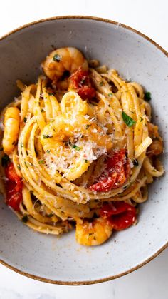 a bowl filled with pasta and shrimp on top of a white countertop next to chopsticks