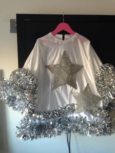 a white shirt with silver stars and tinsels on the front, hanging from a pink hanger