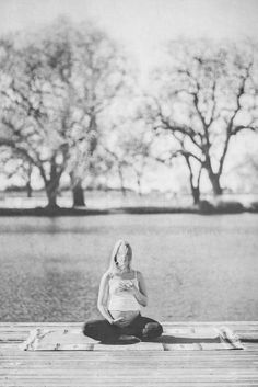 a woman sitting on top of a wooden dock next to trees in the background and water