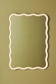 a mirror that is on the wall with a light green background and white trim around it