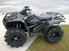 a four - wheeler is parked on the side of the road in front of some grass