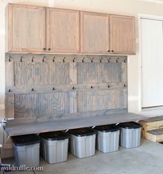 several buckets are lined up in front of a wooden bench with hooks on it