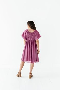 Features Round neckline Short puff sleeve with elastic cuff Elastic waist Smocked back Fully lined Pockets Deep orchid color with shimmer overlay Dress & Lining: 100% Polyester Size + Fit XS 00-2, Small 2-6, Medium 8-10, Large 12-14, X-Large 14-16, 2X 20-22, 3X 24-26, 4X 28-30 Kristin is 5'4", a size 1 and is wearing a Small Jaycie is 5'6", a size 18 and is wearing a 2X Runs true to size. Bust Measurements taken while laying flat and then doubled. They do no account for stretch. Click here for s Chic Knee-length Smock Dress, Puff Sleeve Smock Dress For Beach, Summer Flowy Puff Sleeve Dress With Gathered Neckline, Billowy Solid Dress For Spring, Flowy Smocked Bodice Knee-length Dress, Beach Dresses With Smock And Puff Sleeves, Flowy Knee-length Smocked Dress, Spring Solid Color Billowy Dress, Spring Billowy Solid Color Dress