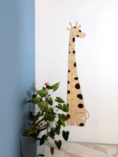 a tall wooden giraffe standing next to a potted plant on a tile floor