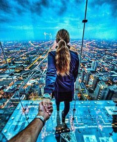 a man and woman standing on top of a tall building looking out at the city