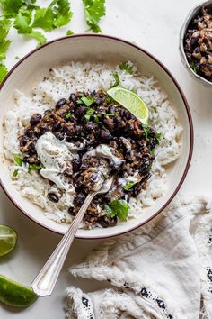 a bowl filled with rice, beans and cilantro on top of a table