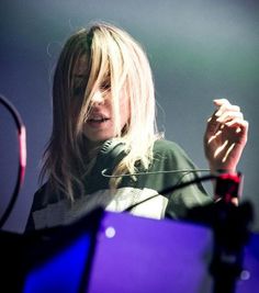 a woman standing in front of a microphone and holding her hand up to the side