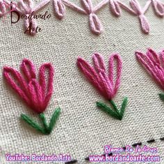 pink flowers are embroidered onto the side of a white piece of cloth with green stems