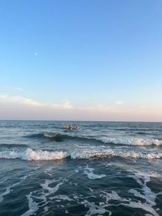 two people in the ocean on surfboards with waves coming towards them and one person swimming