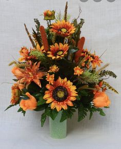 a green vase filled with lots of orange flowers