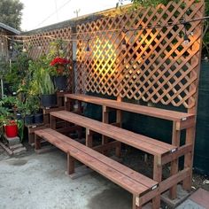 a wooden bench sitting in front of a trellis on top of a building next to potted plants