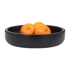 three oranges in a black bowl on a white background