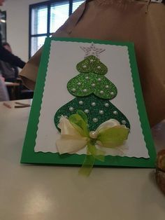 a card with a christmas tree on it sitting on a table next to some donuts