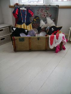 an old suitcase filled with hats and other items on the floor in front of a window