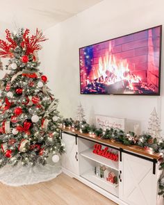 a decorated christmas tree with red and silver ornaments in front of a flat screen tv